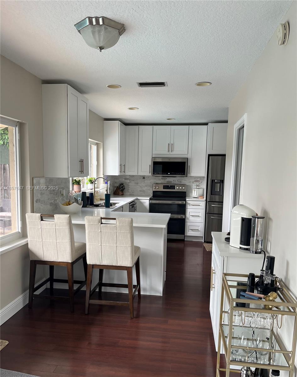 5217 Southwest 87th Avenue Cooper City, FL 33328 - Photo 3 of 8 a kitchen with a dining table chairs and a refrigerator