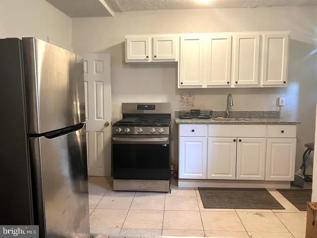 a kitchen with granite countertop a refrigerator sink and cabinets
