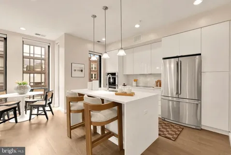 a kitchen with kitchen island a dining table chairs refrigerator and wooden floor