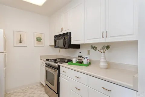 a kitchen with white cabinets and appliances