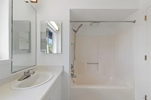a bathroom with a tub shower vanity and a sink