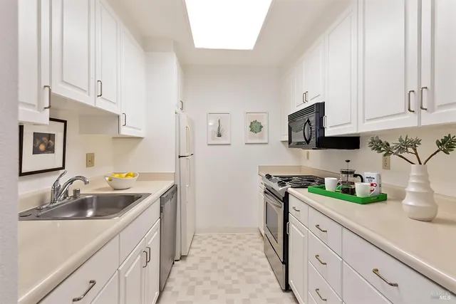 a kitchen with stainless steel appliances granite countertop white cabinets a sink and dishwasher
