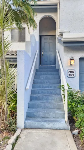 a view of a house with palm trees and a small yard