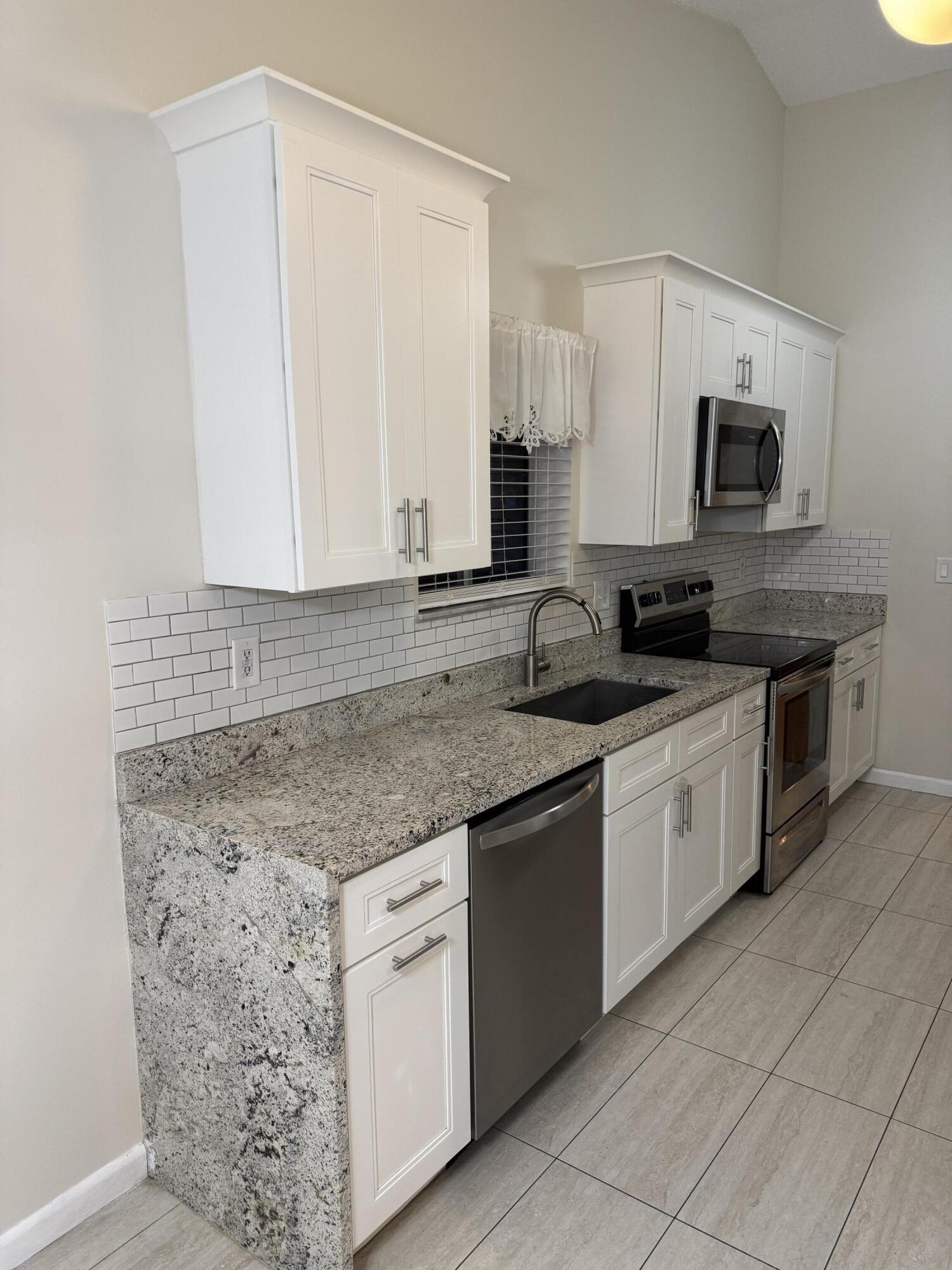 9777 Nickels Boulevard, Unit 705 Boynton Beach, FL 33436 - Photo 11 of 41 a kitchen with stainless steel appliances granite countertop a sink and a stove