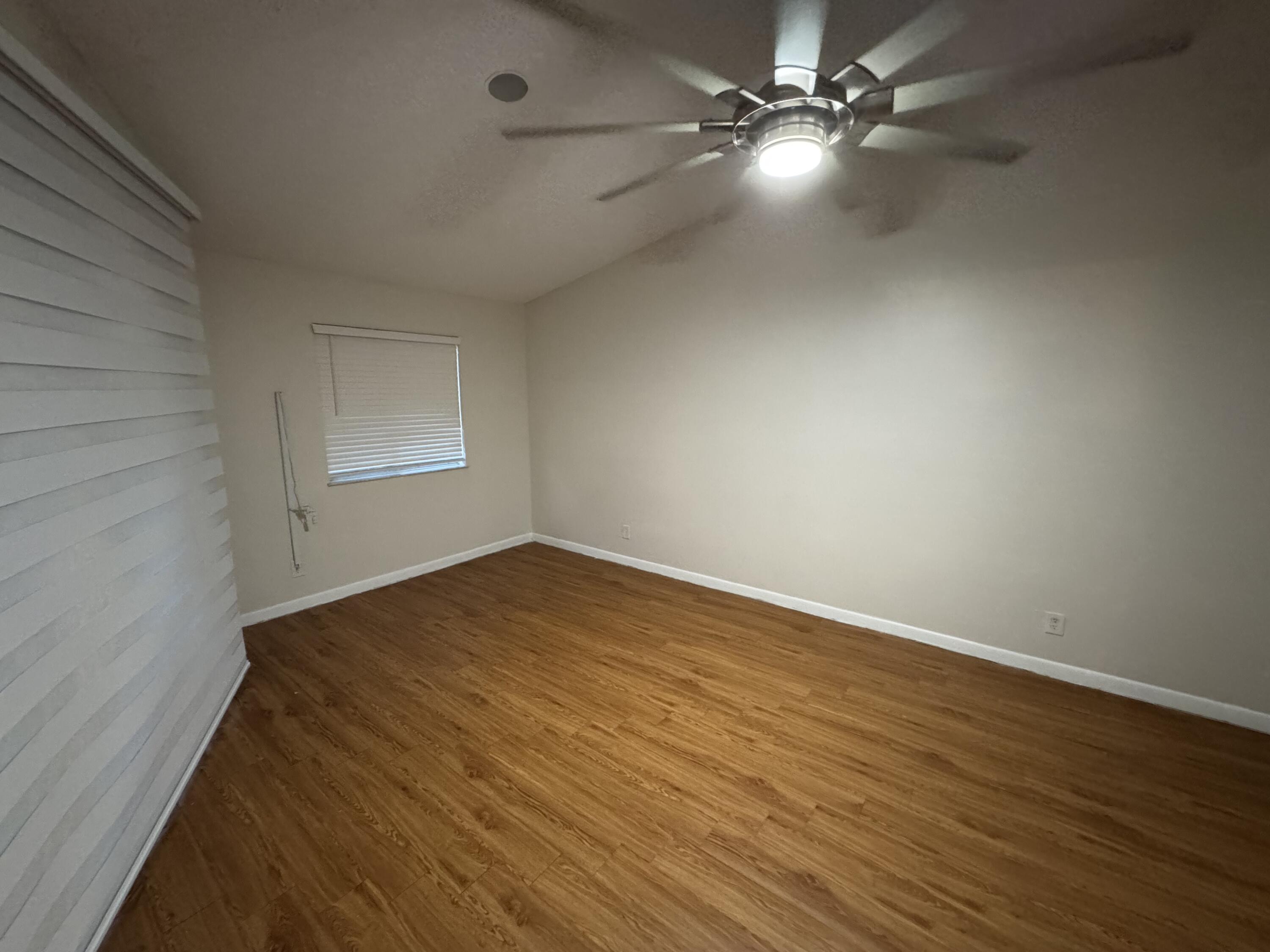 9777 Nickels Boulevard, Unit 705 Boynton Beach, FL 33436 - Photo 23 of 41 an empty room with wooden floor fan and windows