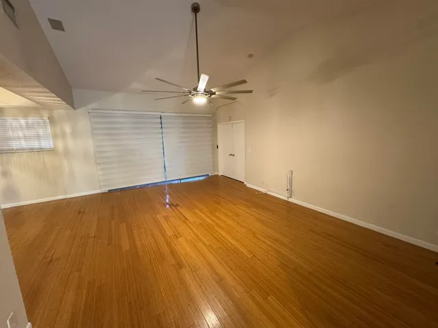 a view of empty room with wooden floor and fan