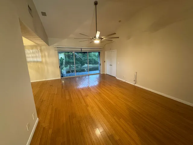 a view of empty room with wooden floor and fan