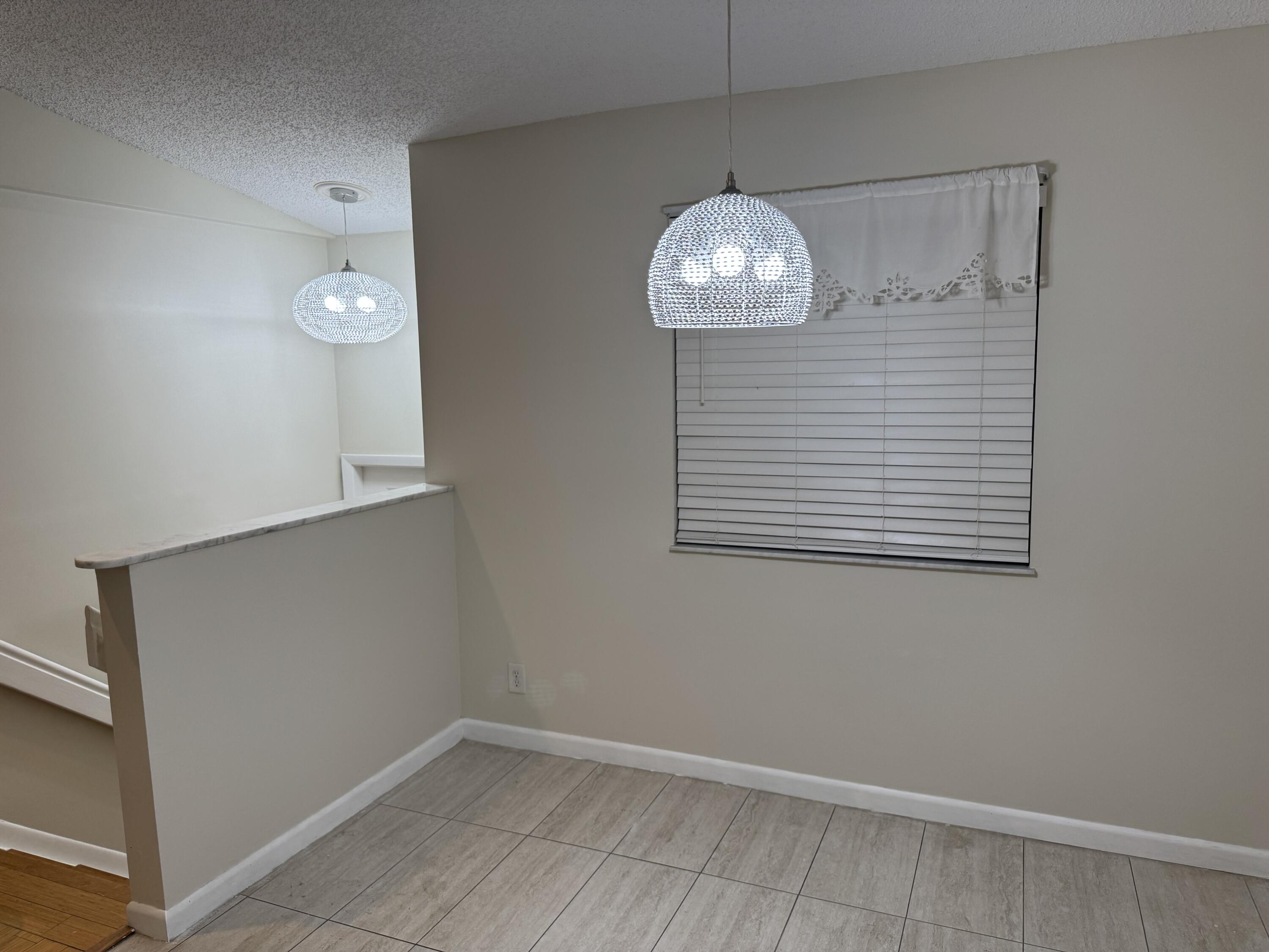 9777 Nickels Boulevard, Unit 705 Boynton Beach, FL 33436 - Photo 9 of 41 an empty room with wooden floor and chandelier