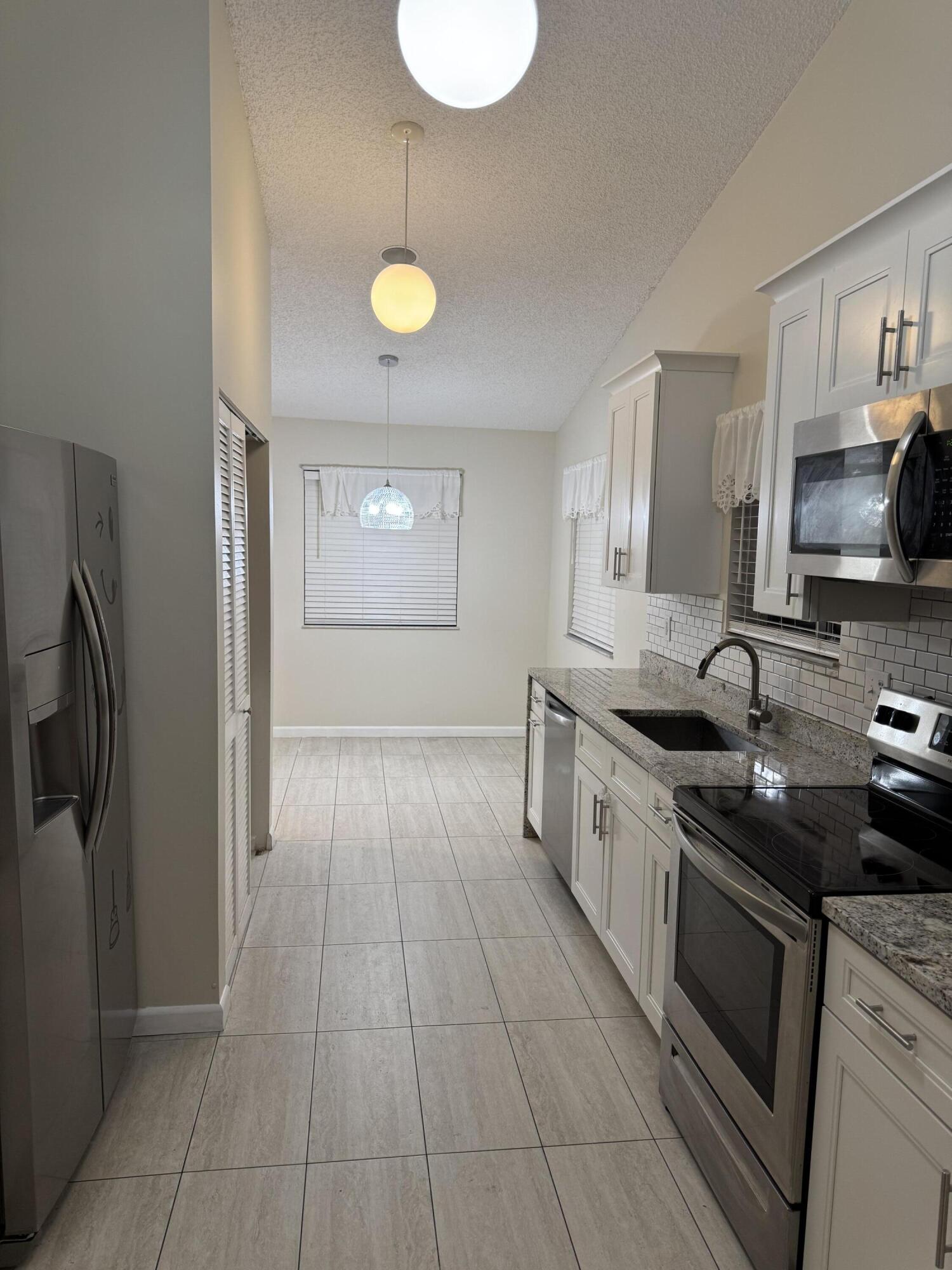 9777 Nickels Boulevard, Unit 705 Boynton Beach, FL 33436 - Photo 10 of 41 a kitchen with stainless steel appliances granite countertop a stove a sink and a refrigerator