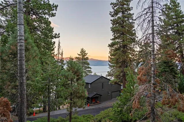 an aerial view of a house with outdoor space and trees all around