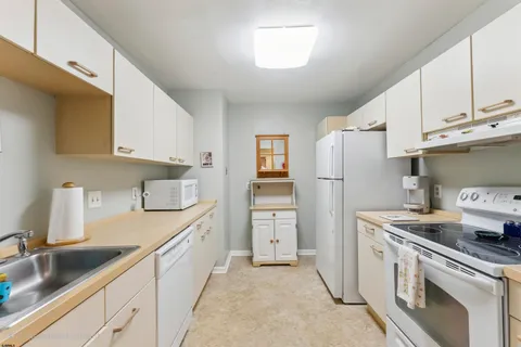 a kitchen with white cabinets and refrigerator