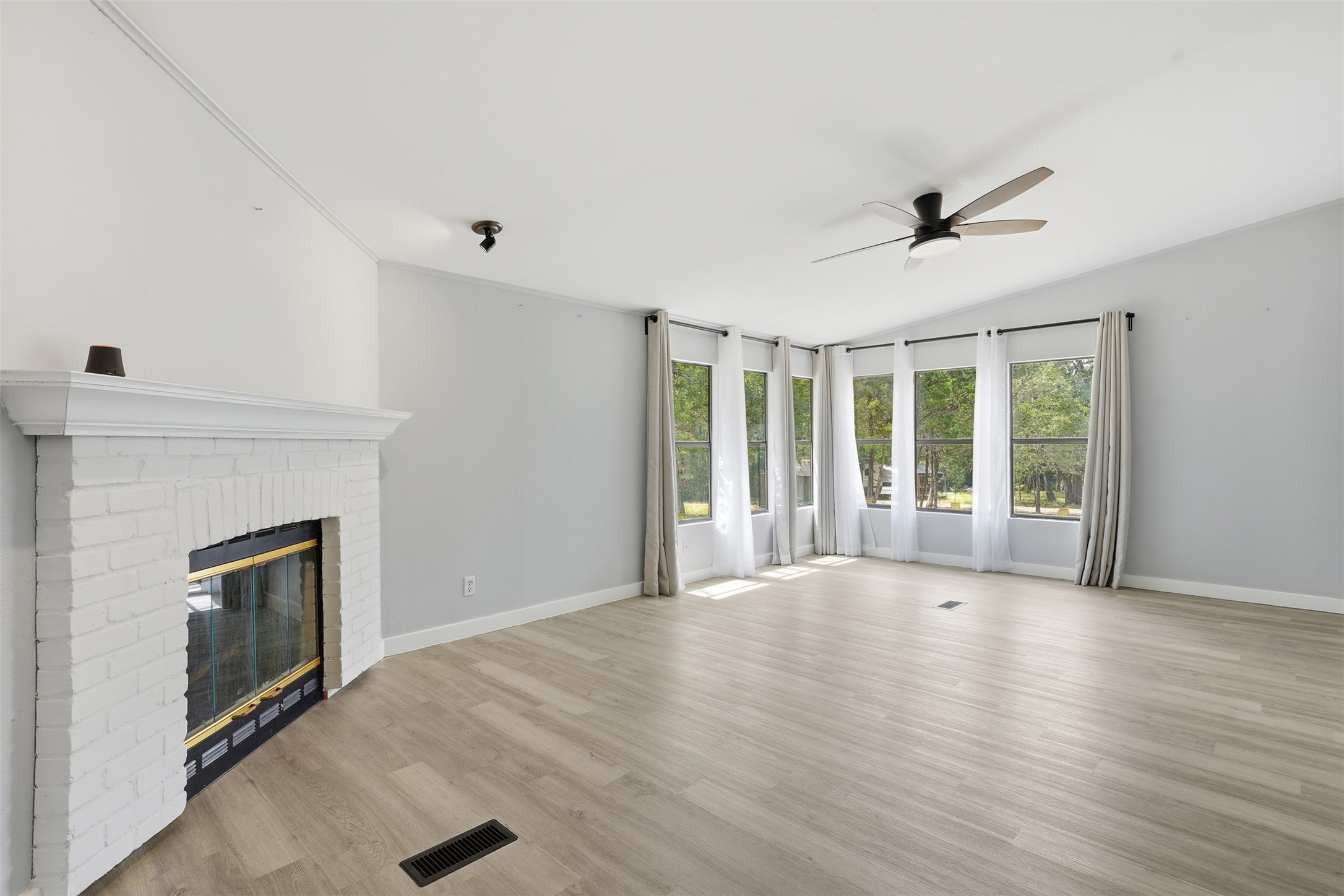 154 Antioch Road Smithville, TX 78957 - Photo 18 of 32 A spacious living room with a charming white brick fireplace and abundant natural light from a wall of windows.