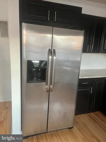 a kitchen with a refrigerator and wooden floor