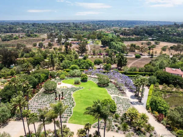 an aerial view of residential houses with outdoor space and trees