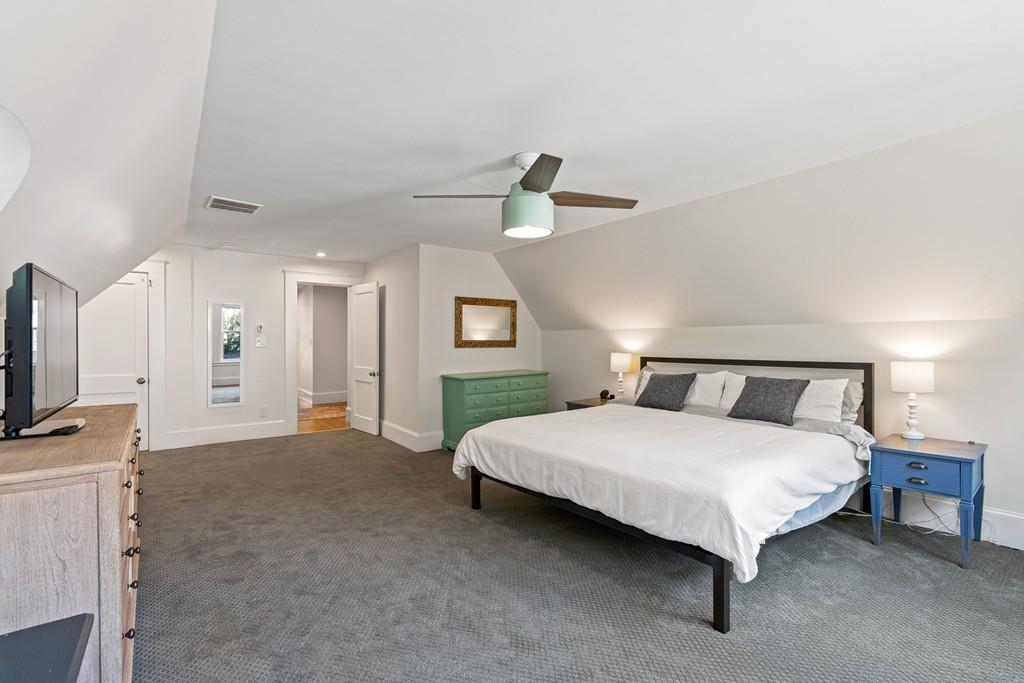 125 Walnut Street Dedham, MA 02026 - Photo 4 of 37 a spacious bedroom with a bed a mirror on dresser and a chandelier