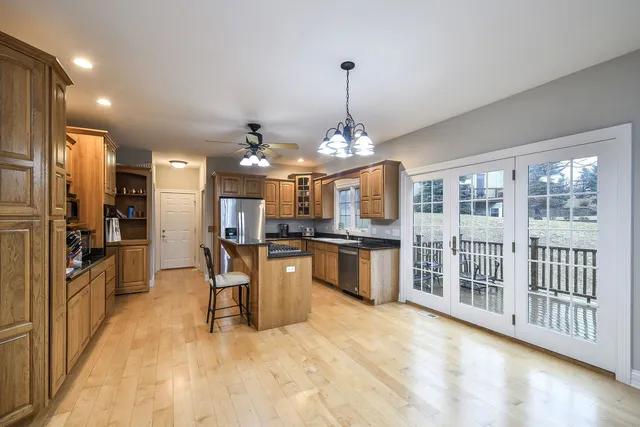 a view of a kitchen with kitchen island a large counter top stainless steel appliances and cabinets