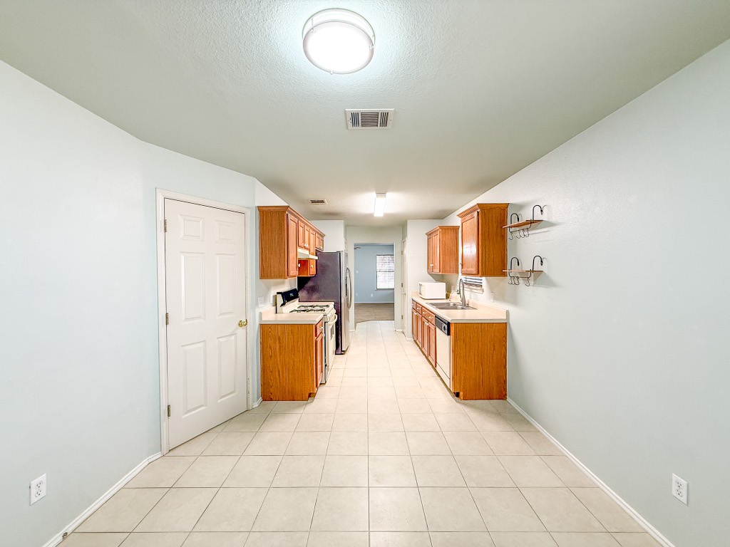 11101 Franklins Tale Loop Austin, TX 78748 - Photo 21 of 39 Kitchen with light countertops, white appliances, brown cabinets, open shelves, and a textured ceiling