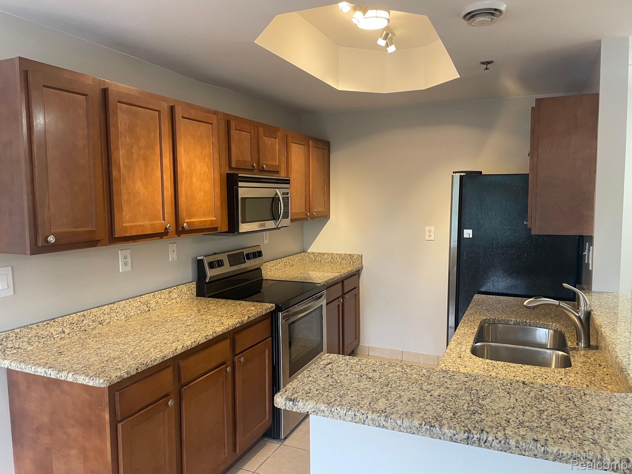 2727 East Maple Road Birmingham, MI 48009 - Photo 14 of 29 Kitchen featuring wood cabinetry, light-toned countertops, stainless steel appliances, and a double basin sink with a gooseneck faucet