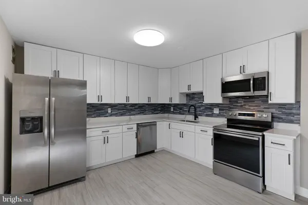 a kitchen with stainless steel appliances granite countertop a refrigerator a stove a sink and white cabinets