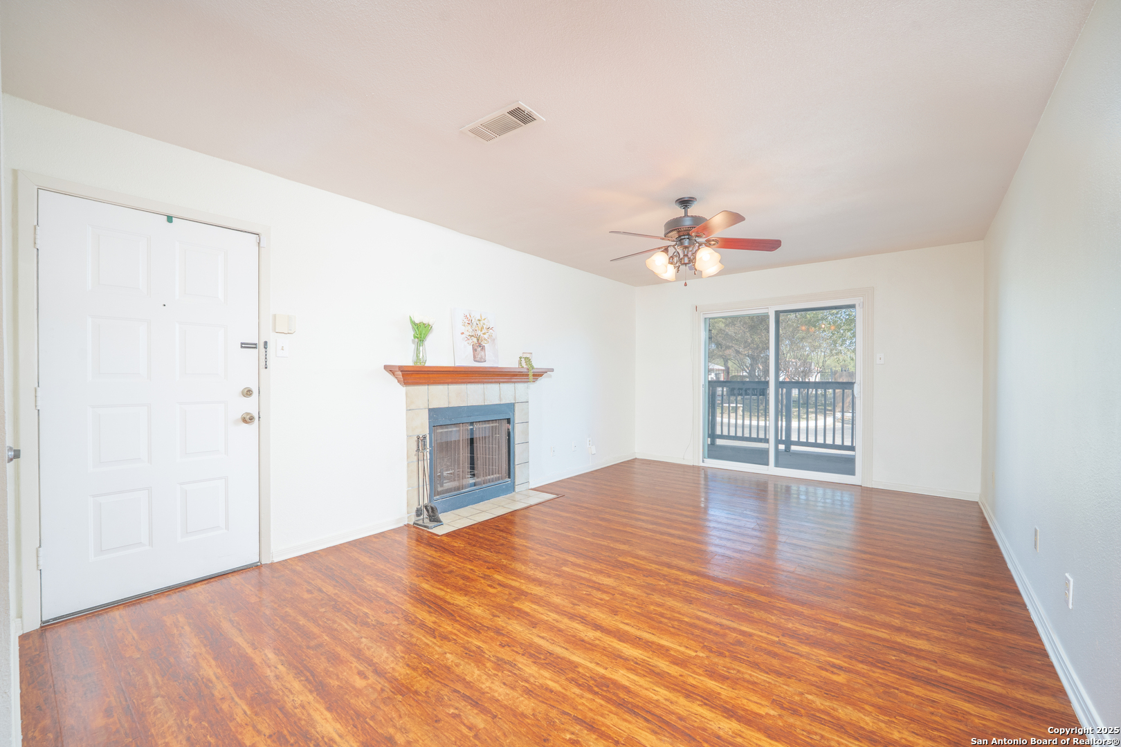 a view of an empty room with a window and wooden floor