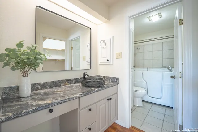 a bathroom with a granite countertop sink and a mirror