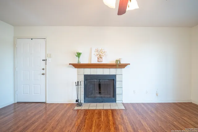 a view of an empty room with wooden floor and a fireplace