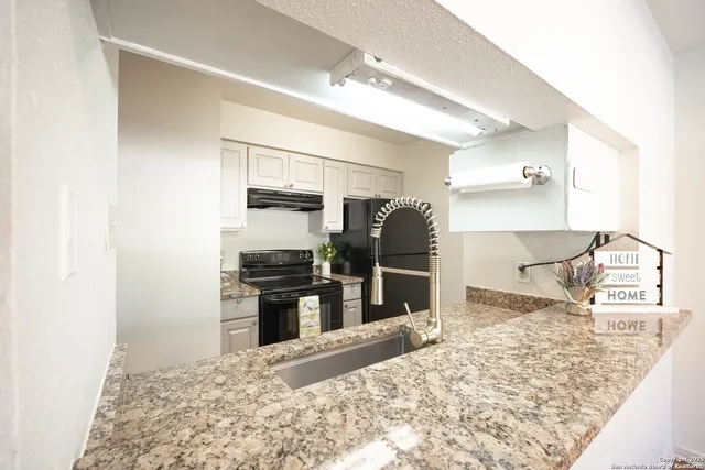 a kitchen with stainless steel appliances kitchen island granite countertop a refrigerator and a sink