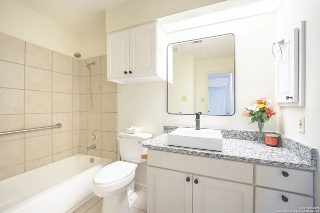 a bathroom with a granite countertop sink toilet mirror and bathtub