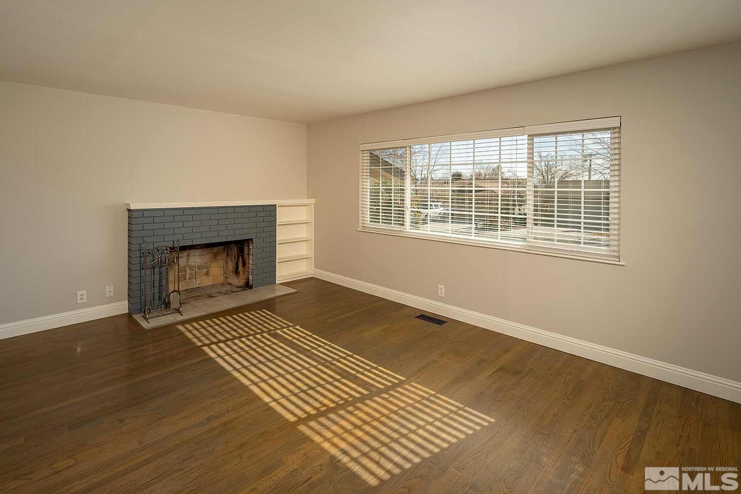 1465 West 12th Street Reno, NV 89503 - Photo 6 of 40 a view of an empty room with wooden floor a fireplace and a window