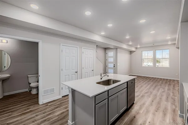a kitchen that has a sink and a stove with wooden floor