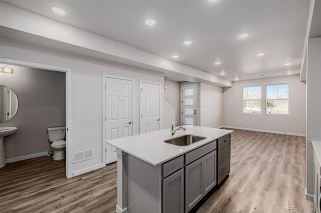 a kitchen that has a sink and a stove with wooden floor