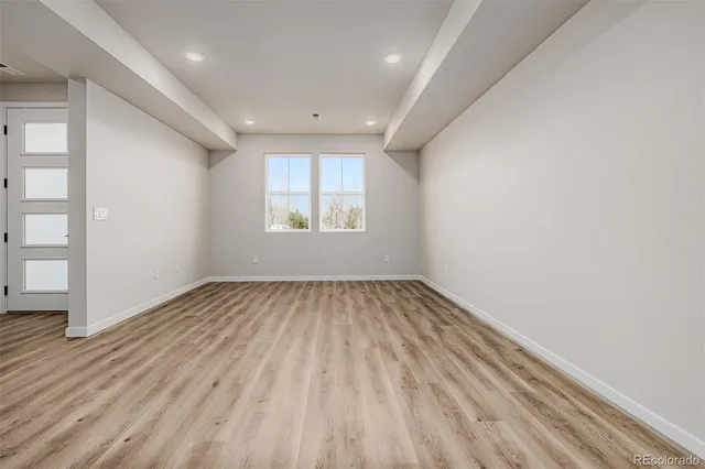 an empty room with wooden floor and windows