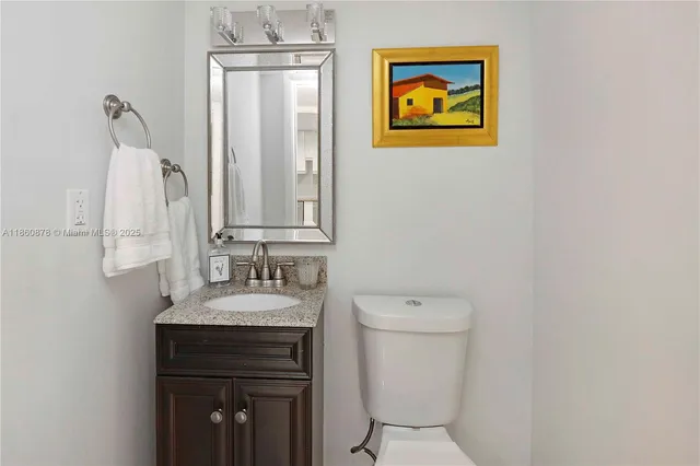 a bathroom with a granite countertop toilet sink and mirror
