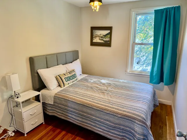 a bedroom with a bed wooden floor and window