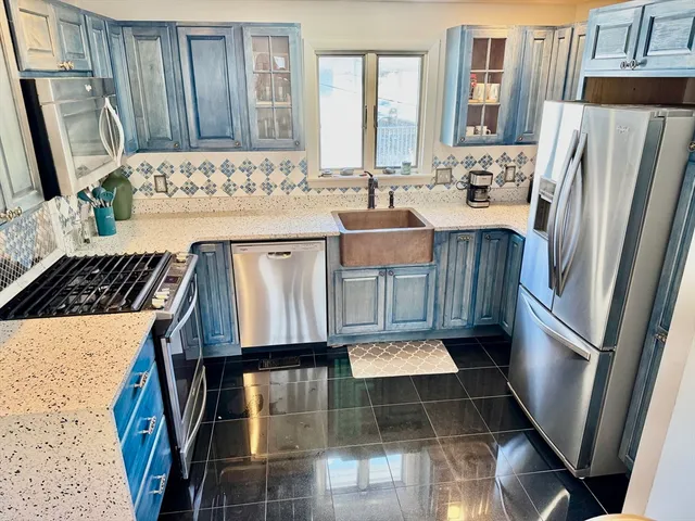 a view of kitchen with granite countertop a sink a stove a refrigerator and cabinets