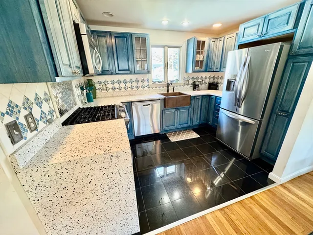 a kitchen with stainless steel appliances kitchen island granite countertop a refrigerator a stove and a sink with wooden floor