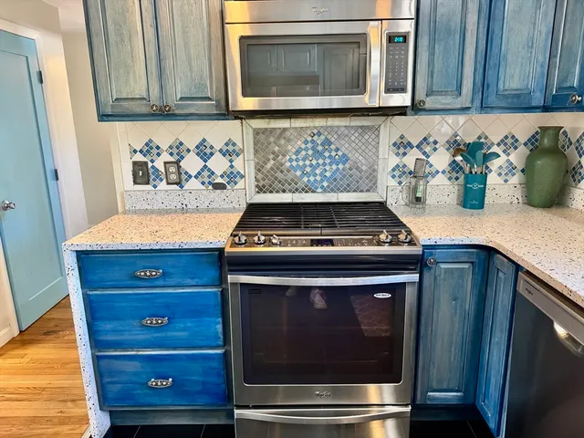 a kitchen with granite countertop white cabinets and stainless steel appliances