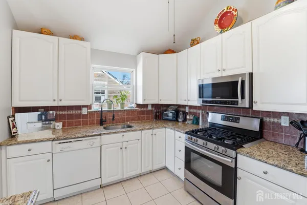 a kitchen with stainless steel appliances granite countertop a sink a stove and a microwave