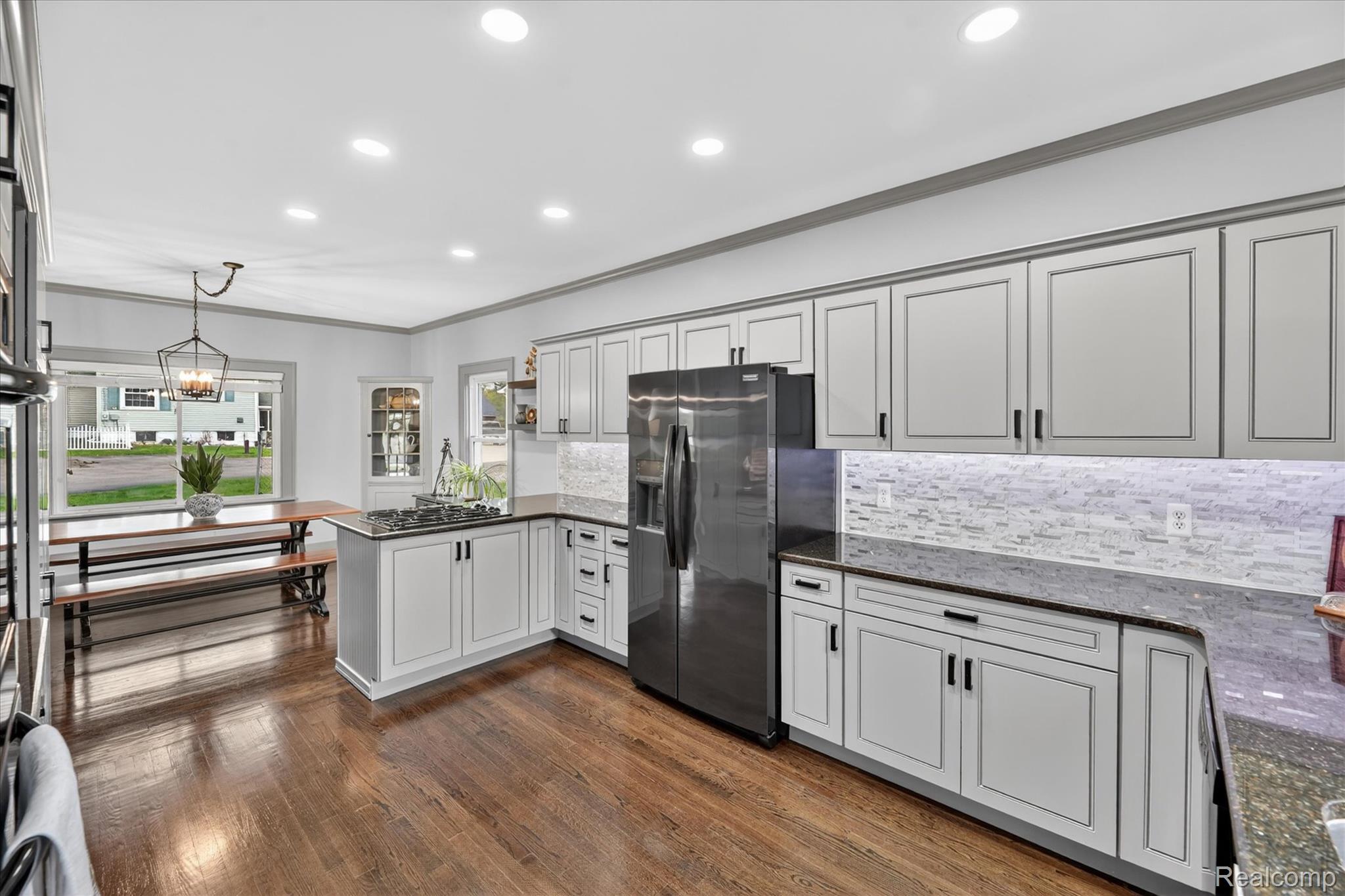 12409 Fenton Road Fenton, MI 48430 - Photo 12 of 61 Kitchen featuring a peninsula, dark stone counters, stainless steel appliances, decorative backsplash, and crown molding