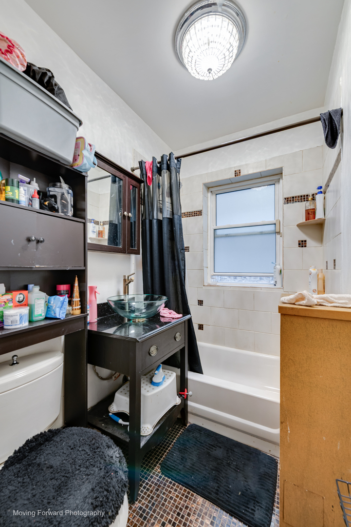 8213 South Indiana Avenue Chicago, IL 60619 - Photo 9 of 25 a bathroom with a bathtub a mirror and shower