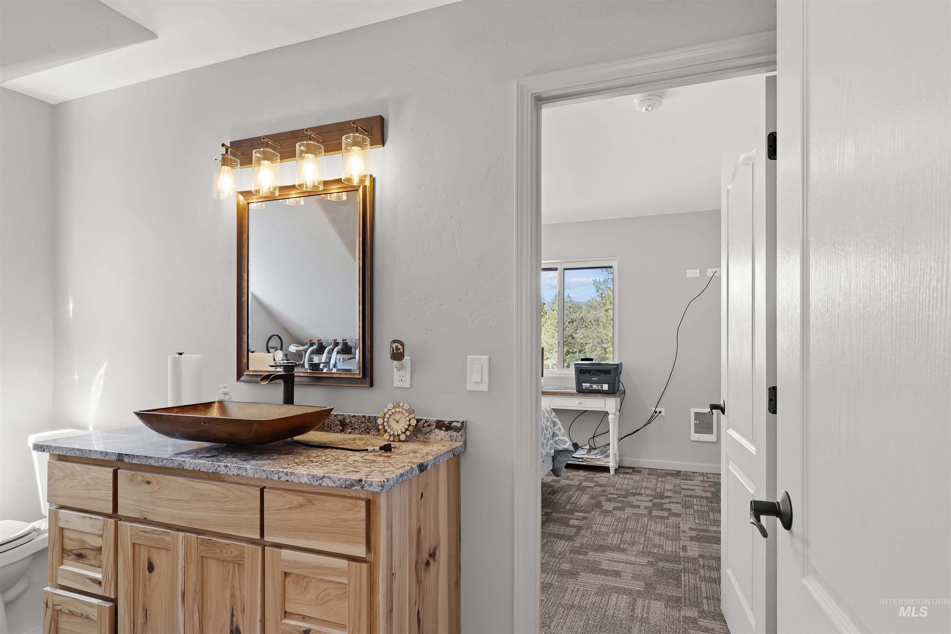507 Bearlea Road Anatone, WA 99401 - Photo 13 of 47 Bathroom vanity featuring a vessel sink, stone countertop, wood-finish cabinetry, and a four-light fixture