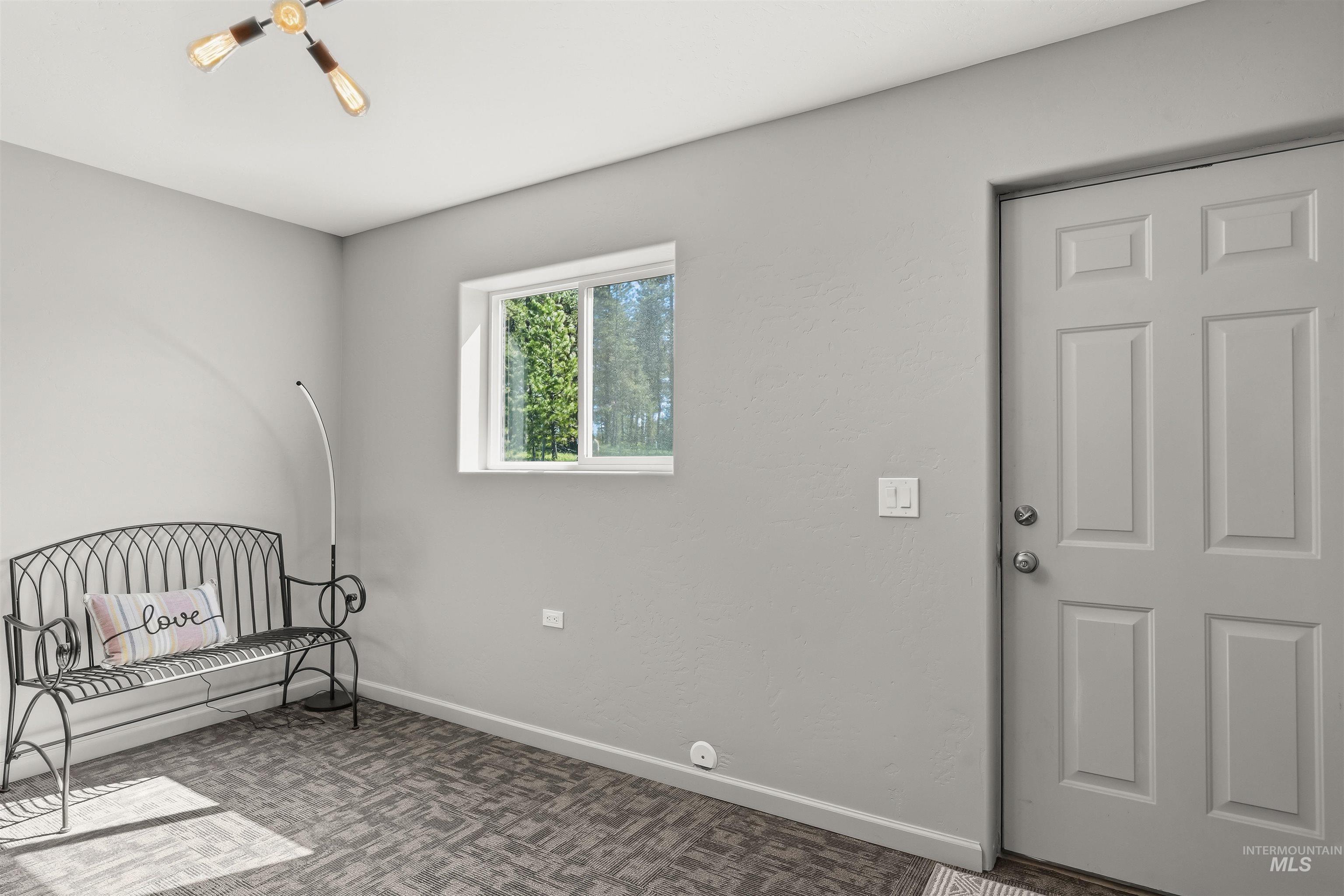 507 Bearlea Road Anatone, WA 99401 - Photo 20 of 47 Interior room featuring a window, gray walls, patterned carpet flooring, and a paneled entry door