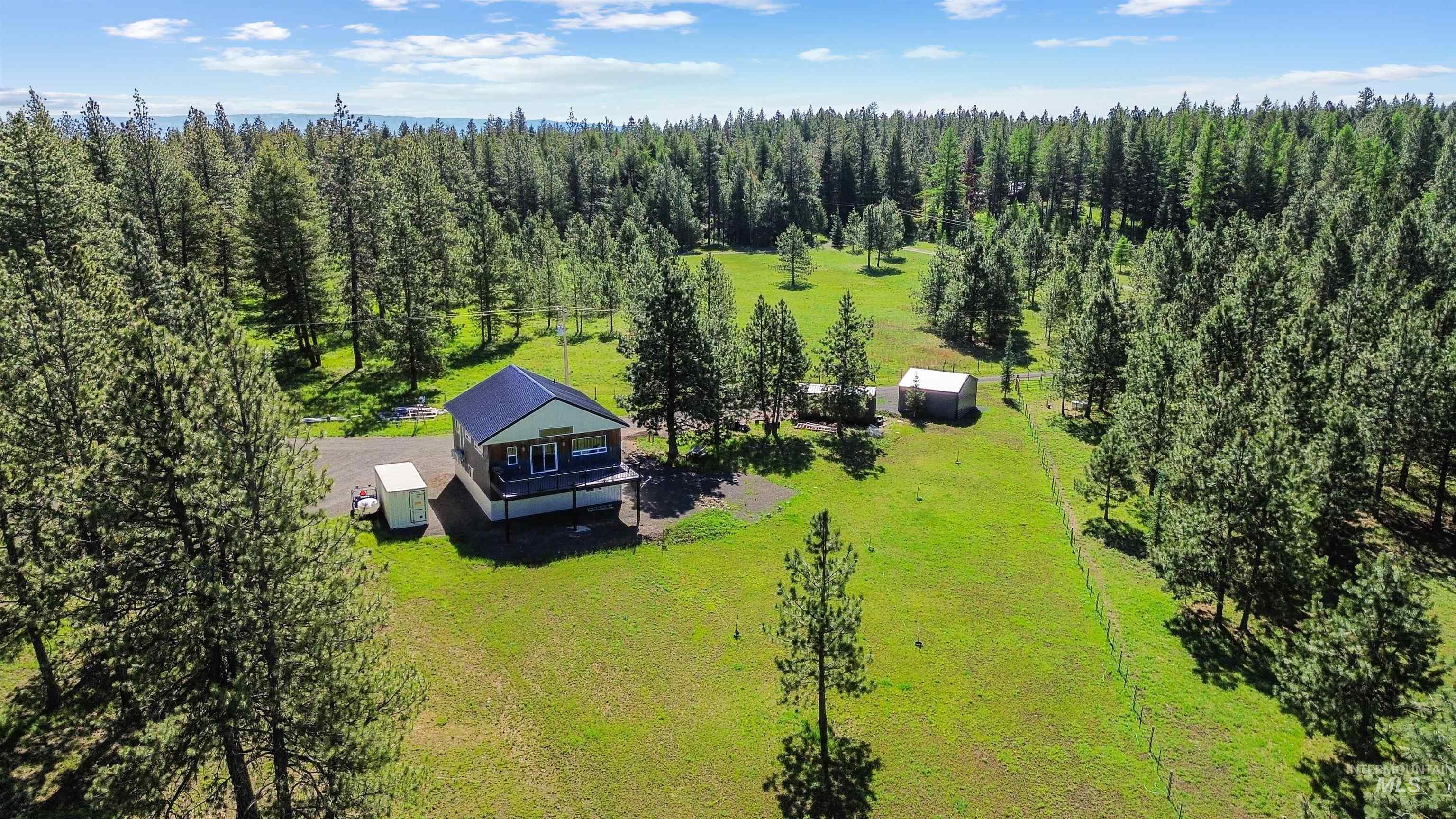 507 Bearlea Road Anatone, WA 99401 - Photo 34 of 47 Expansive treed acreage featuring a residence with a dark roof and light siding, an outbuilding, and a gravel driveway