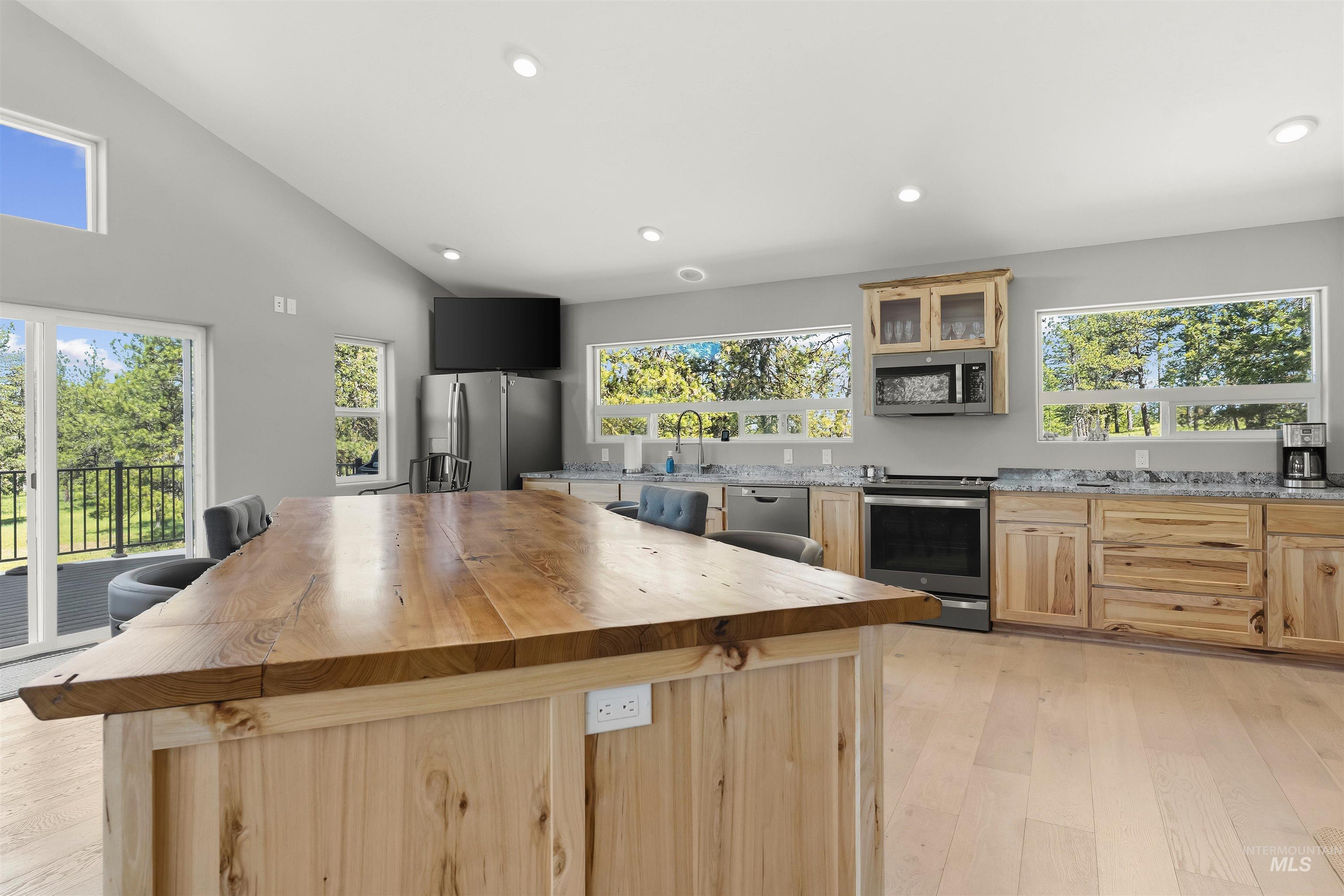 507 Bearlea Road Anatone, WA 99401 - Photo 37 of 47 Vaulted ceiling kitchen featuring a natural wood-finish island with a power outlet, light wood-finish cabinetry, stainless steel appliances, and Granite countertops