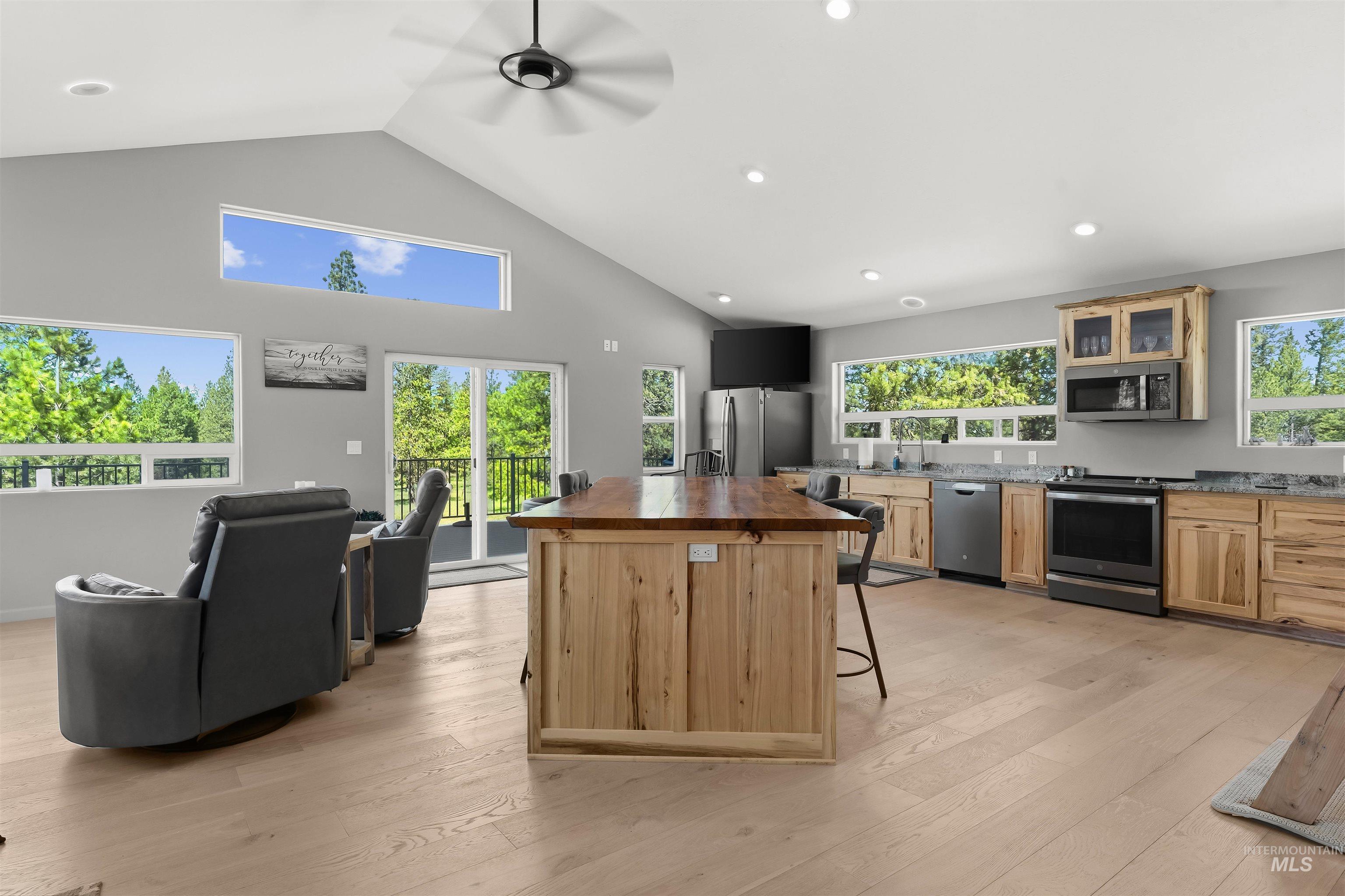 507 Bearlea Road Anatone, WA 99401 - Photo 39 of 47 Spacious kitchen and living area featuring a vaulted ceiling with a ceiling fan, light wood-finish flooring, and multiple large windows