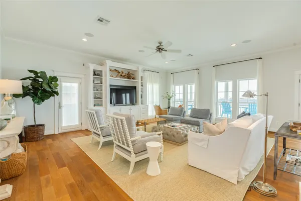 a living room with furniture a flat screen tv and floor to ceiling window