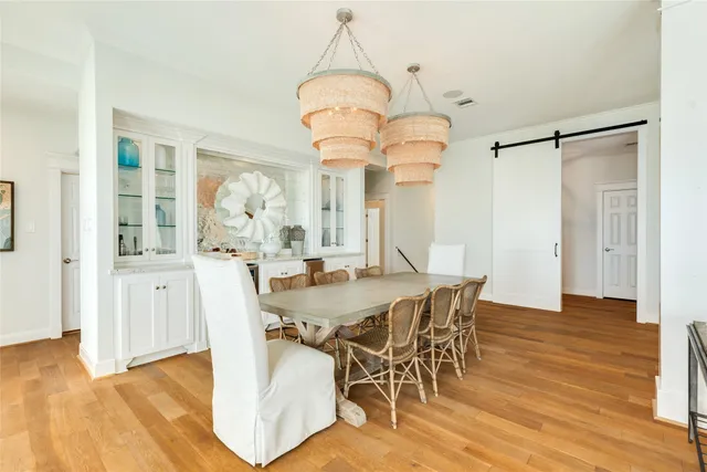 a dining room with wooden floor a chandelier a wooden table and chairs