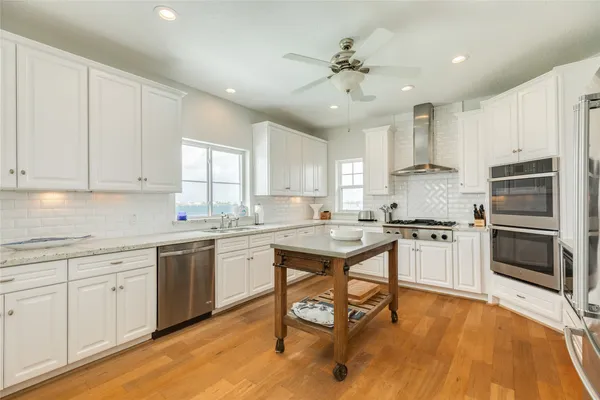a kitchen with a refrigerator a sink dishwasher a stove and white cabinets with wooden floor