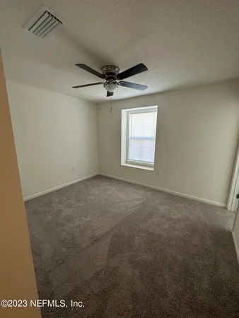 an empty room with windows and ceiling fan