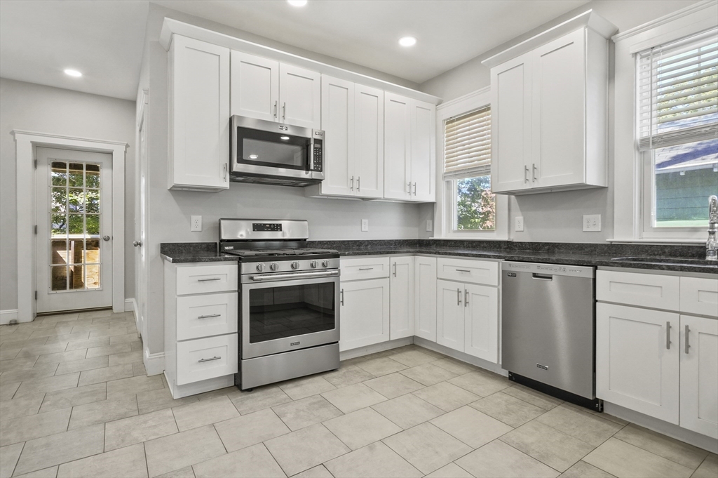 a white kitchen with granite countertop white cabinets and stainless steel appliances